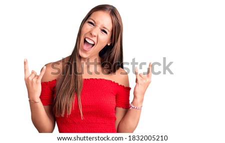 Young beautiful hispanic woman wearing casual clothes shouting with crazy expression doing rock symbol with hands up. music star. heavy concept. 