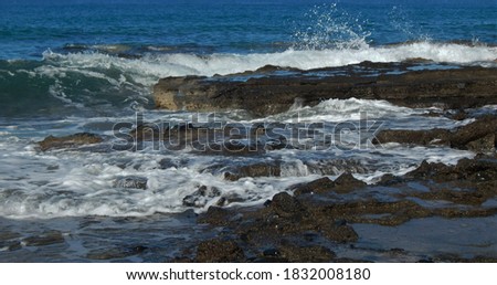 Mediterranean waves are turned into a frothing  water mass as they pour over shoreline rocks and boulders at Agia Marina, Cyprus.