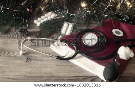 A medical banner with pills, a stethoscope, and Christmas decorations: garlands, toys, and a Santa hat. Copy space. Christmas in medicine.