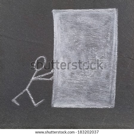 A stick figure pushing a big white block, drawn with chalk on a plate of slate.