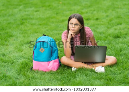  teen girl use computer on green grass in park. child with backpack and notebook.  