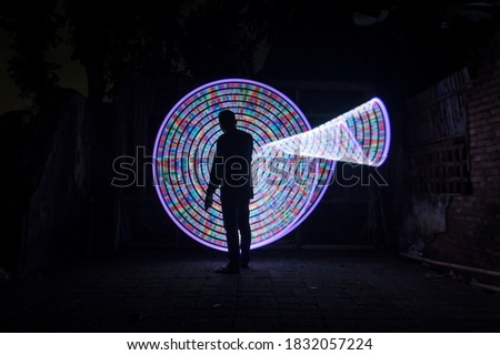 One people standing alone against a abstract circle light painting as the backdrop