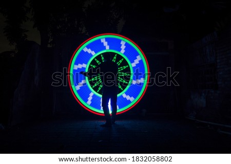 One people standing alone against a green and blue circle light painting as the backdrop