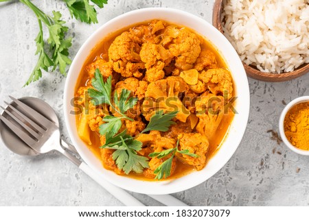 Cauliflower stew with curry, cumin, turmeric and other spices in a white bowl on a grey concrete background top view. Curry roasted cauliflower. Royalty-Free Stock Photo #1832073079