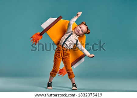 Little child girl in an astronaut costume is playing and dreaming of becoming a spaceman. Isolated blue background. Copy space Royalty-Free Stock Photo #1832075419