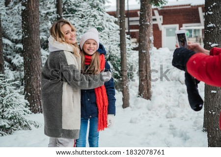 Mom and daughter pose for dad during a weekend trip to the woods during the Christmas holidays.