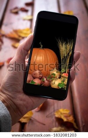 Mobile phone with a picture of a thanksgiving harvest on a leaf covered deck