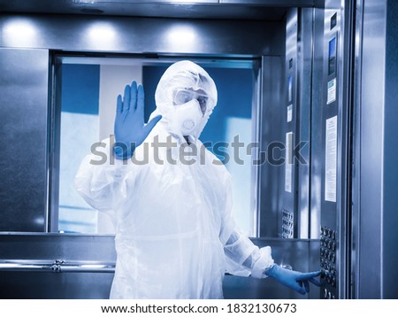 Man wearing protective uniform in elevator show stop sign. Covid 19 pandemic