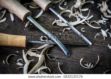 Top view of sculpture workshop. Overhead photo of Woodworking chisels ranges, wood shavings, and other carving tools. Drawing and sculpting of a wooden printing block. and Carved Wood Block tools. Royalty-Free Stock Photo #1832135176