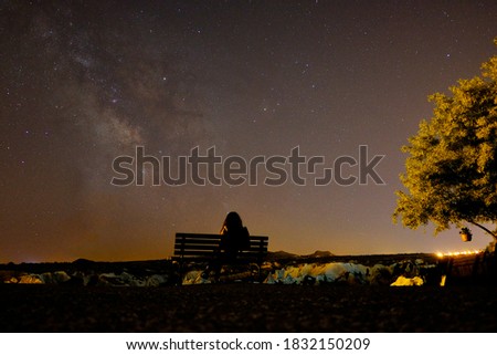 rear view of woman sitting against milky way