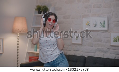 Happy young woman dancing at home, having fun. It celebrates the taste of happiness with dance moves.