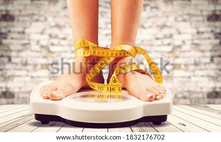 Woman on weight scales and measuring tape Royalty-Free Stock Photo #1832176702