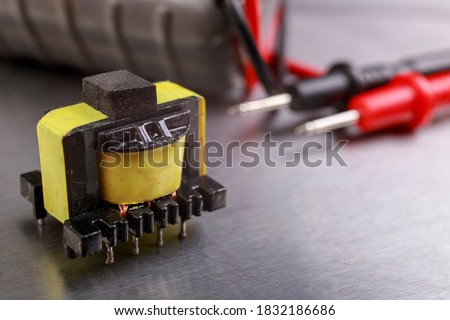 Electric coil and electric meter. Measurement work in an electrical workshop. Metallic background.