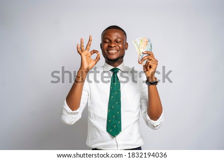 Handsome Black millennial businessman holding money and making quality sign on a studio background-concept on Africans and business