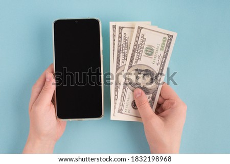 Top above first person overhead close up view photo of female hands taking money holding phone with touchscreen empty touch screen display isolated blue color background
