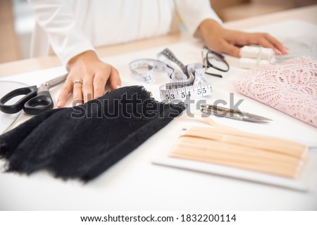 Step 1 process of sewing underwear and clothes, woman tailor cuts blanks for panties from black lace.