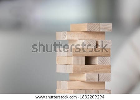 Crop close up of wooden stack tower isolated on grey blurred background. Strategic educational game for logic and business solution development. Learning, teambuilding activity, teamwork concept.