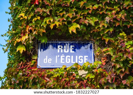 Church street ("Rue de l'Eglise" in French) plate on house overgrown with ivy. France. Europe autumn countryside travel. 