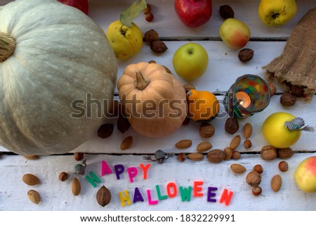 Retro style photo with a Halloween theme. Pumpkins, autumn fruits, a lamp and little monsters.The inscription "Halloween" is laid out with plastic letters in an unusual way.Focus foreground.