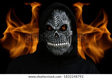 Defocus man in death mask with fire flame in eyes on dark black hell fire flame background.Halloween holiday concept. Death carnival costume. Scary death portrait. Dark horror. Out of focus. No focus 