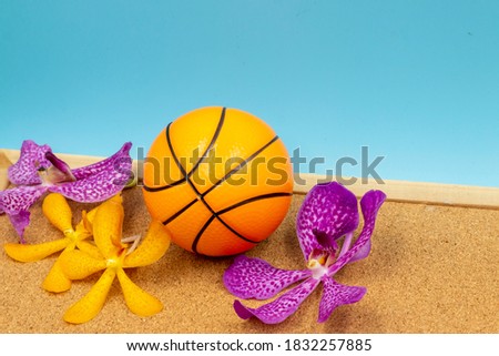 Basketball with orchid flower on wooden floor