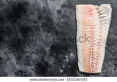 Raw Norwegian skrei cod fish fillet. Black background. Top view. Copy space
