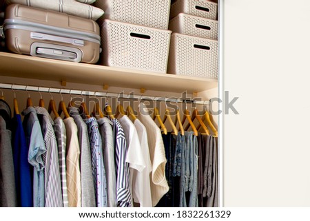 Wardrobe with perfect order clothes in blue and light shades on the hangers and things in containers. The concept of organizers and cleanliness in the house Royalty-Free Stock Photo #1832261329