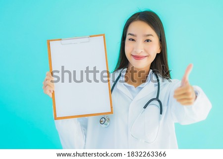 Portrait beautiful young asian doctor woman with empty card billboard banner on blue isolated background