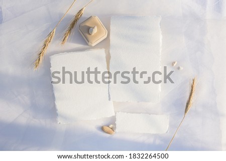 Blank paper card with copy space . Wedding ring and wheat on white textile background. Styled stock photography for display your design, lettering, font, illustration, wedding stationary. Flat lay