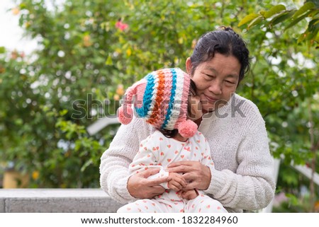 Adorable asian granddaughter is happy kissing her grandmother with fully happiness moment in the green garden, concept of love and relation of difference generation in family lifestyle