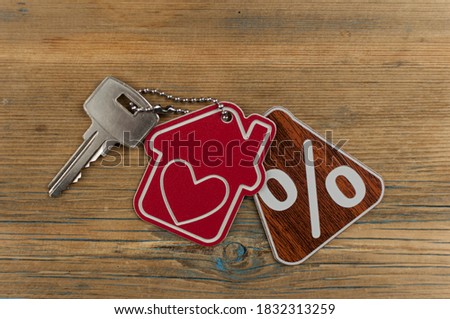 red percent sign and model house with key on wooden background . real estate concept