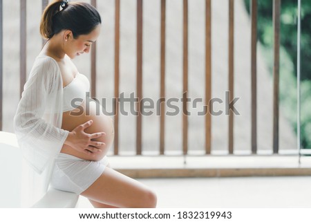 A Beautiful woman Asian pregnant  posing a happy smile Sit by the bathtub Royalty-Free Stock Photo #1832319943