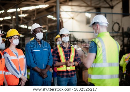 A team of technicians, foreman and engineers Accepting assignments from a manager or supervisor In the morning meeting before work In which everyone wear surgical masks to prevent the coronavirus Royalty-Free Stock Photo #1832325217