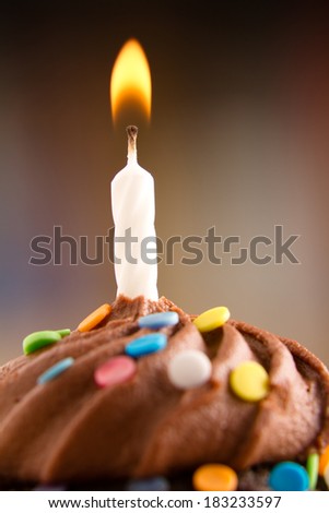Birthday Cupcake - This is a shot of a delicious birthday cupcake with a candle sitting on a wooden table top. Shot with a shallow depth of field with the focus on the candle.