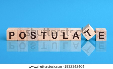 Text POSTULATE on wood cube block, stock investment concept. The text POSTULATE is written on the cubes in black letters, the cubes are located on a blue glass surface.
