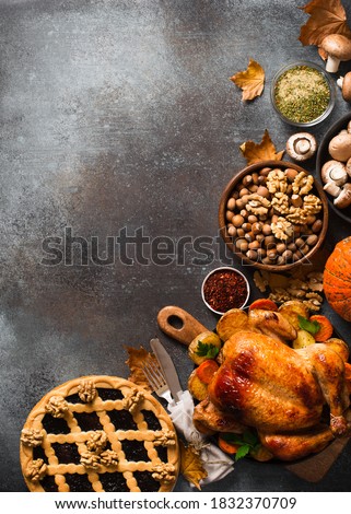 Fall thanksgiving table with roasting chicken or turkey, nuts, pie, pumkins and other food on dark background, rustic, top view, vertical