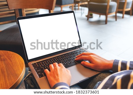 Mockup image of a woman using and typing on laptop computer keyboard with blank white desktop screen in cafe