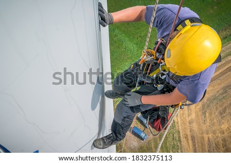 Inspection engineer rappels down a rotor blade of a wind turbine in a North German wind farm. Royalty-Free Stock Photo #1832375113