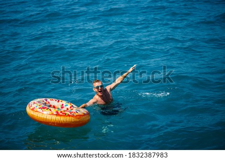 Young man on an inflatable ring in the sea resting and swimming on a sunny day