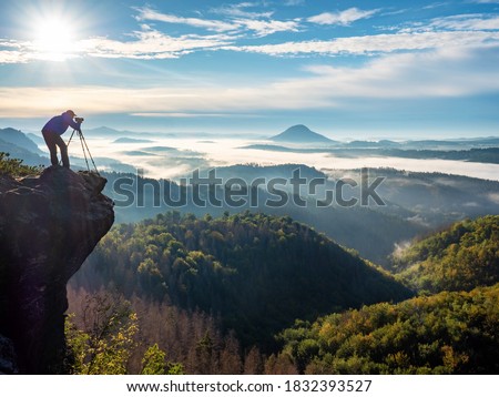 Photographer on mountain witch through viewfinder. Nature photographer taking photo of beautiful morning landscape from top of the mountain