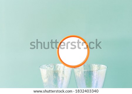 round jar with white space for text on mother of pearl wine glasses on pastel blue clear background