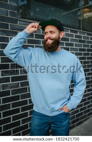 City portrait of handsome hipster guy with beard wearing blue blank sweatshirt with space for your logo or design. Mockup for print