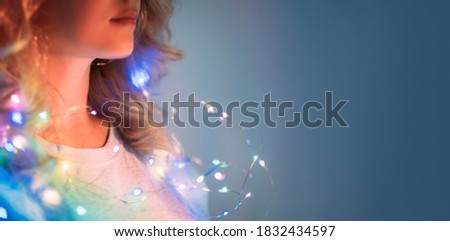 Festive background. Holidays decoration. Cristmas party. New Year celebration. Woman with shiny fairy lights in blur rainbow color gradient glow isolated on navy blue copy space background.