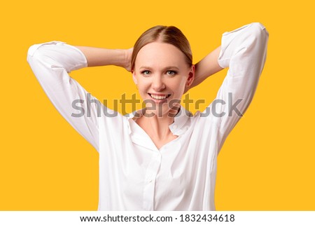 Female beauty. Face skincare. Healthy lifestyle. Anti-aging cosmetology. Cheerful woman with natural makeup in white shirt smiling holding hair back isolated on orange background.
