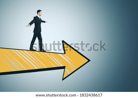 Businessman in suit walking on drawing yellow arrow on gray background. Business and challenge concept.