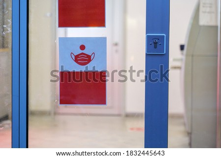 Selected focus at White protective face mask symbol, red sign on the glass of window at the entrance of the bank for social distancing and new normal during epidemic of COVID-19.