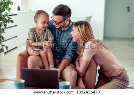 Young family looking movies on laptop together at home.