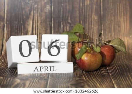 April 6. Day 06 of month. Calendar cube on wooden background with red apples, concept of business and an important event. Spring season.