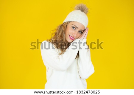 Young beautiful blonde woman wearing winter clothes sleeping tired dreaming and posing with hands together while smiling.