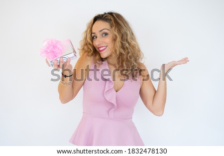 Portrait of a pretty smiling woman holding gift box and looking at camera isolated over white background